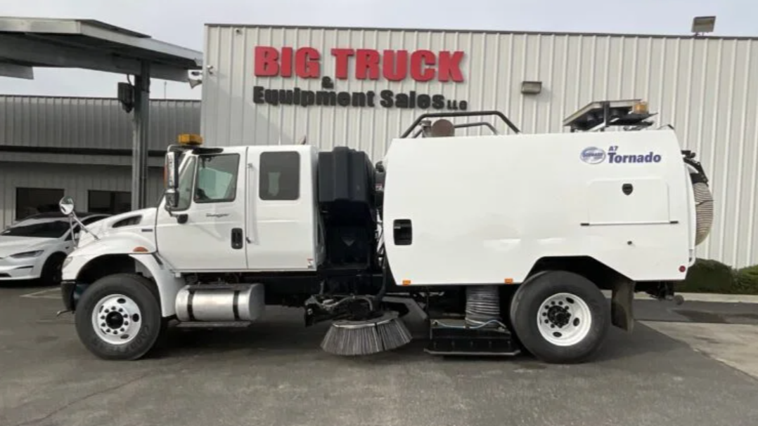 Side view of a white sweeper truck